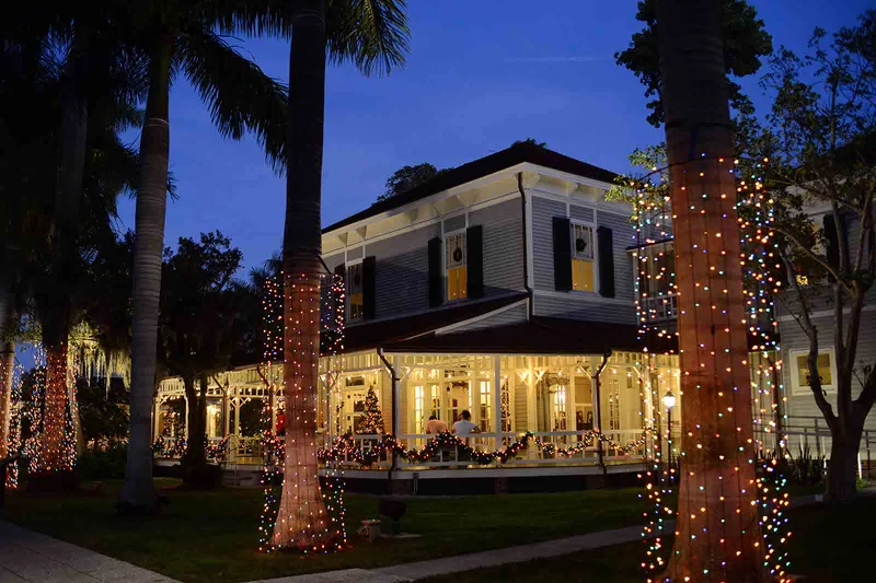 Edison and Ford Winter Estates home and palm trees wrapped in colorful holiday lights at night