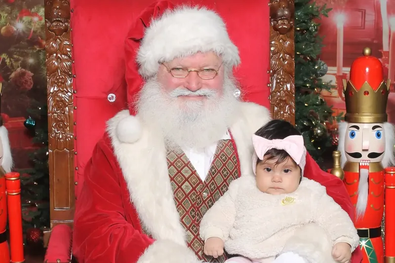 Santa on his throne holding a baby for a holiday photo at Edison Mall