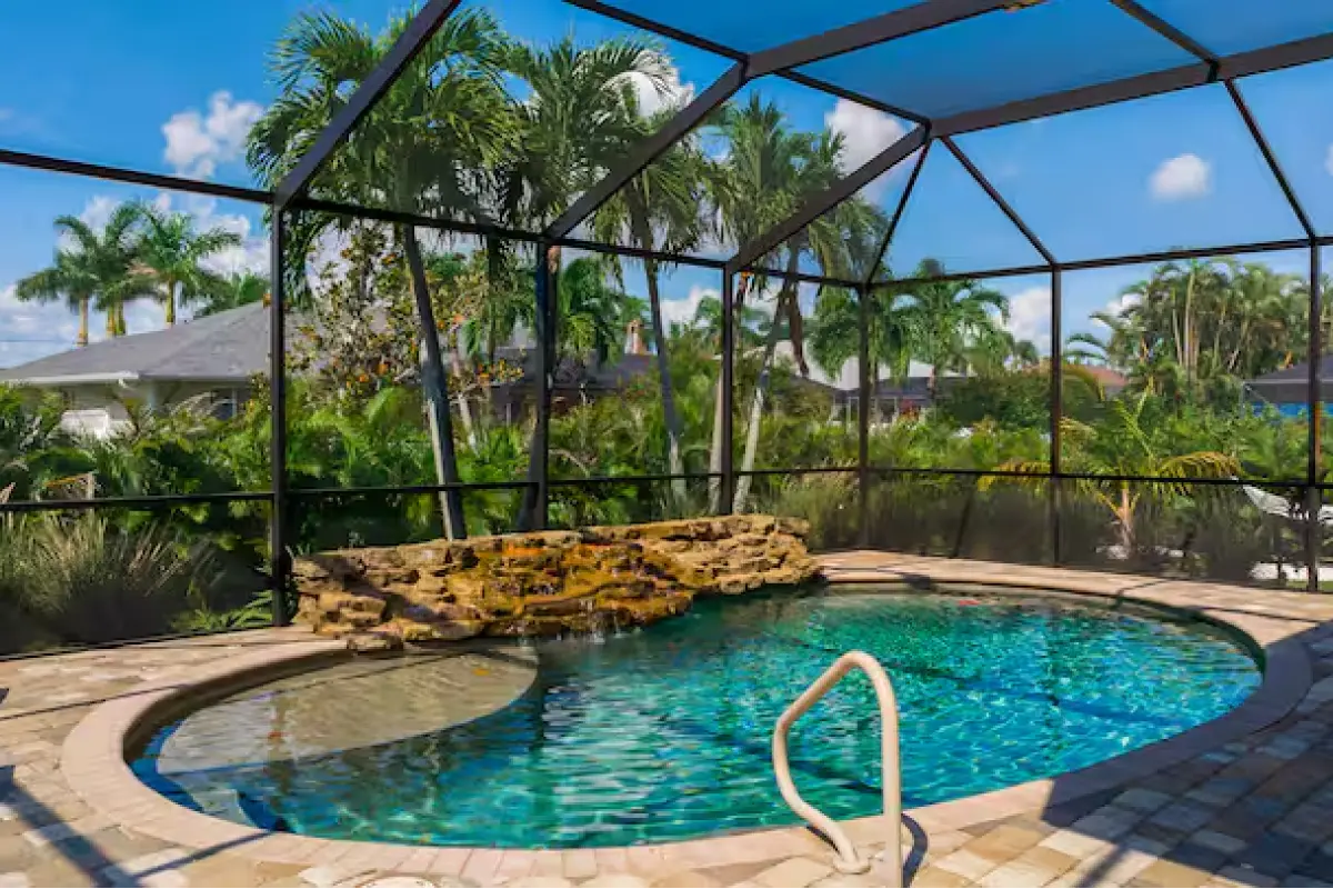 Heated pool inside the screened lanai with palm trees at Beachy Keen in Cape Coral