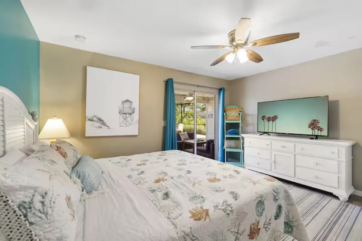 King bedroom with ceiling fan and coastal bedding