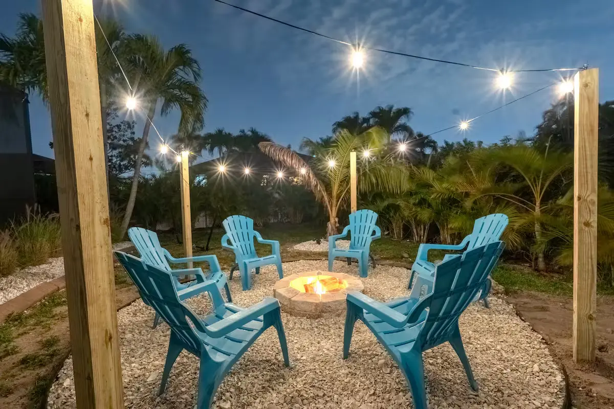 Fire pit with Adirondack chairs and string lights in the backyard
