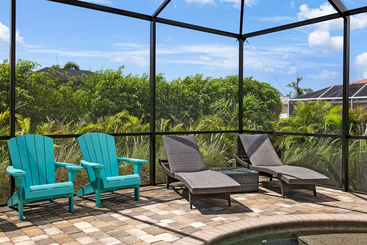 Lounge chairs beside the pool inside the screened lanai